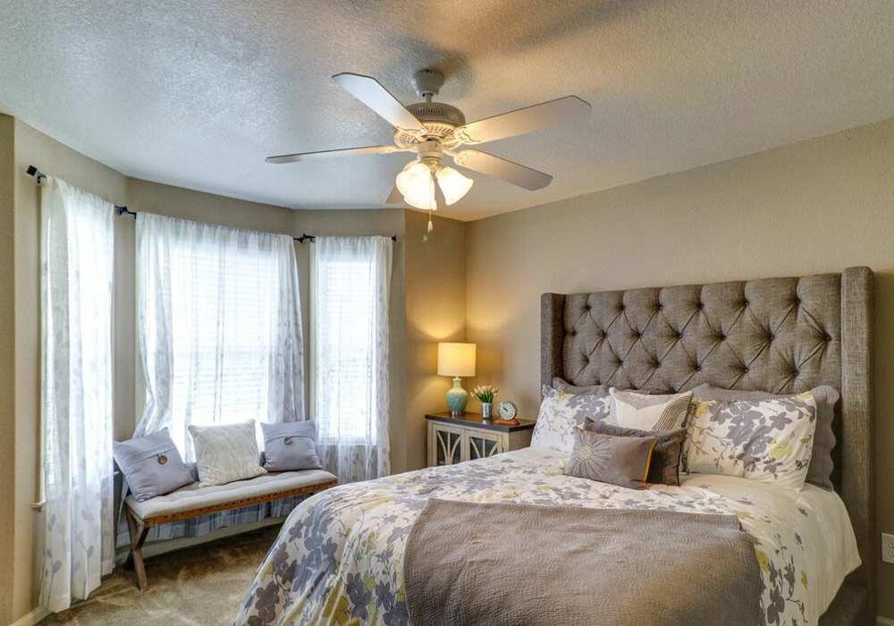Spacious bedroom with king size bed, side table lamp, ceiling fan and large window at The Reserve at Kanapaha in Gainesville, Florida