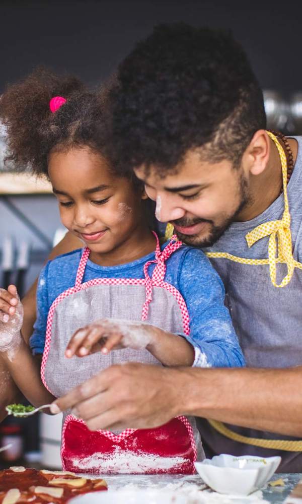 Father helping his kid in cooking at The Abbey on Lake Wyndemere in The Woodlands, Texas