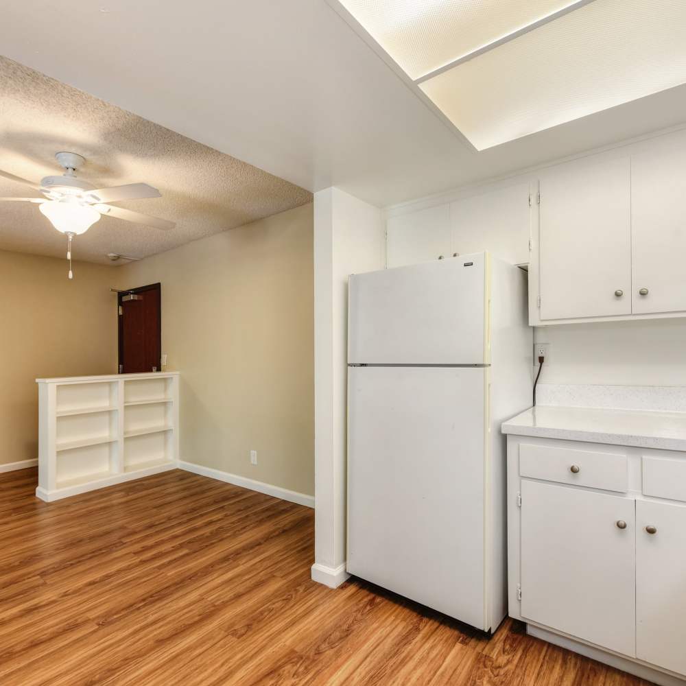 Kitchen with white appliances and cabinetry and living/dining room at Fayette Arms Apartments in Mountain View, California, 
