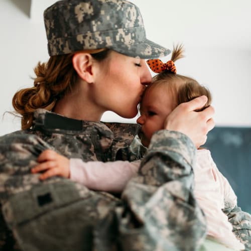 A mother in a military uniform kissing her daughter at South Mesa II in Oceanside, California