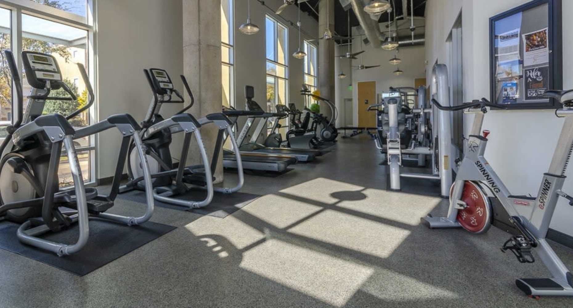 Fully-equipped gym with treadmills, weight machines, and flat-screen TVs at Flatiron District at Austin Ranch in The Colony, Texas