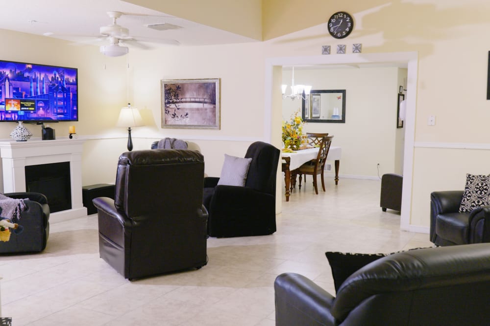 Lounge seating with black leather couches and television at The Club at Wellington in Wellington, Florida