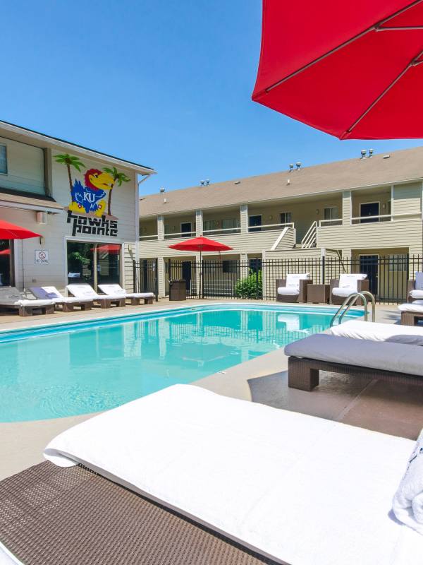 Salt water swimming pool surrounded by lounge chairs and umbrellas at Hawks Pointe in Lawrence, Kansas