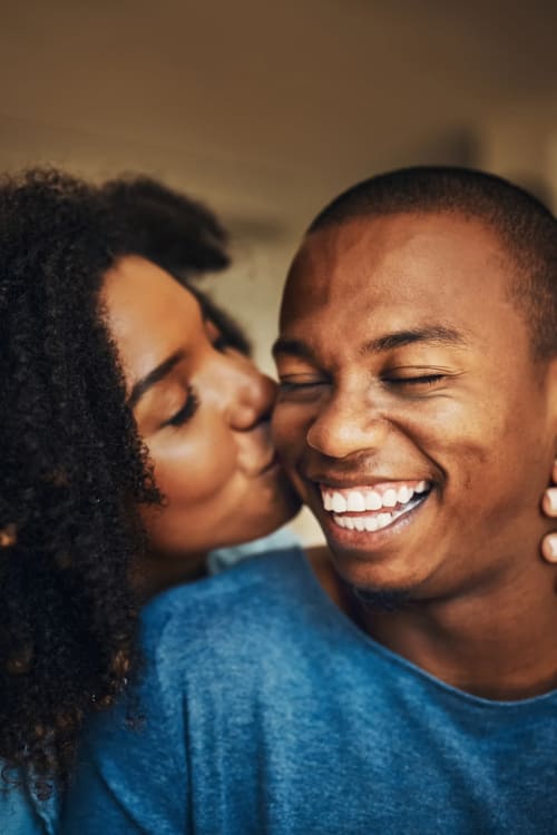 Cute couple kissing with smiles on their face near The Envoy Apartments in Washington, District of Columbia