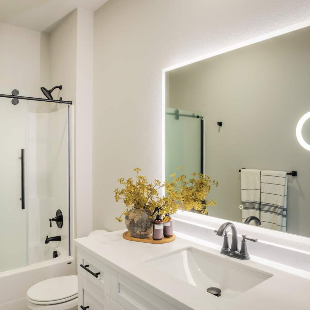 Bright bathroom with vanity light, mirror, sink. commode and glass bathtub at InterUrban 2.0 in Billings, Montana