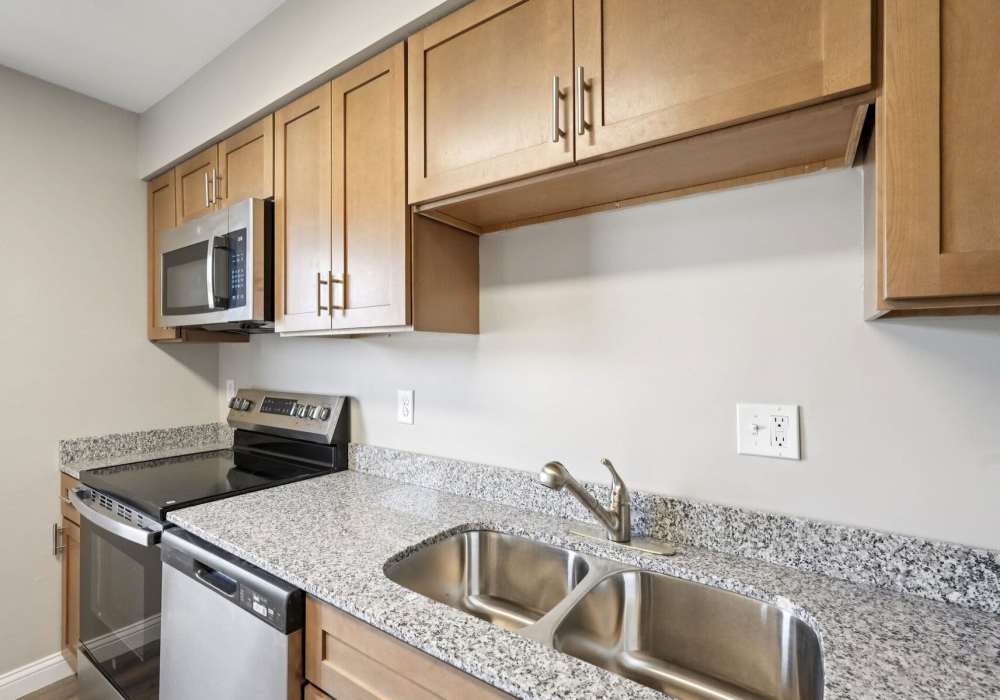 Kitchen with stainless steel appliances and wooden cabinets at Charleston Square Apartments in Columbus, Indiana