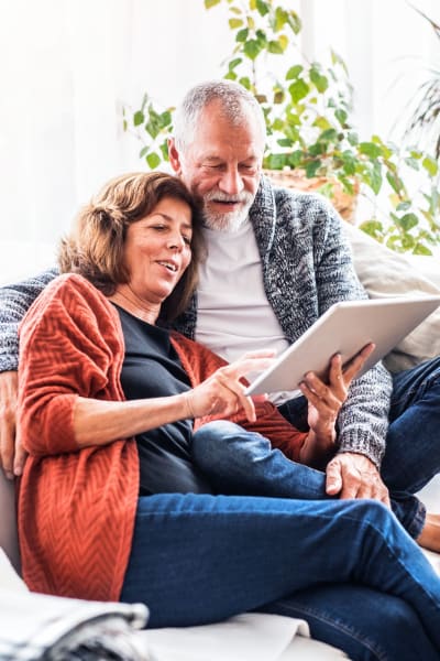 Residents couple surfing the web on a tablet device in their spacious home at The Pointe at Siena Ridge in Davenport, Florida