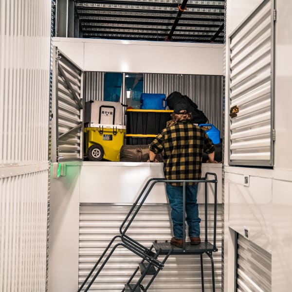 Man adds some camping gear to his elevated storage locker at StorQuest Self Storage