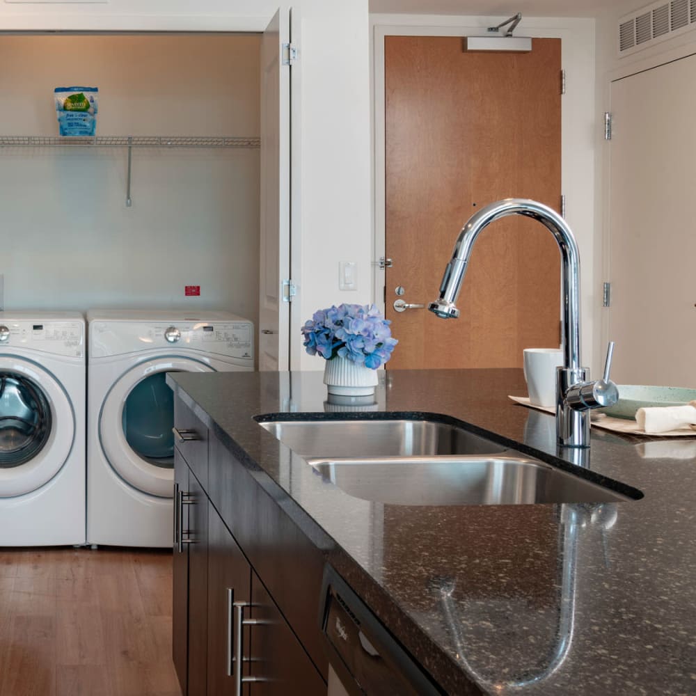 Dual-basin sink and pantry with full-size washer and dryer in a model apartment's kitchen at CitiTower in Orlando, Florida