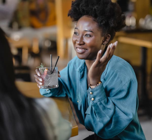 A smiling woman holding a drink in a restaurant near Evergreens at Mahan in Tallahassee, Florida