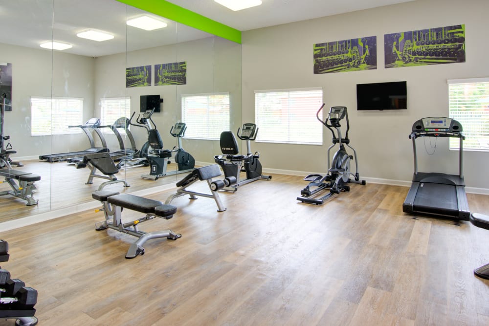 A fitness center with individual workout stations at Running Brook Apartments in Miami, Florida