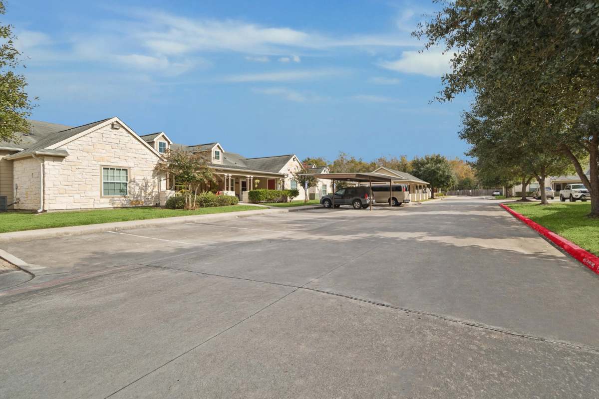 Exterior view of apartment with parking area at Trinity Garden Apartment Homes in Liberty, Texas