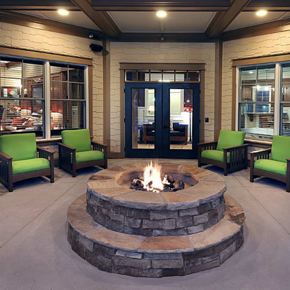 Cozy outdoor fire pit surrounded by vibrant green seating, perfect for relaxing evenings at Avonlea Square in Smyrna, Georgia.