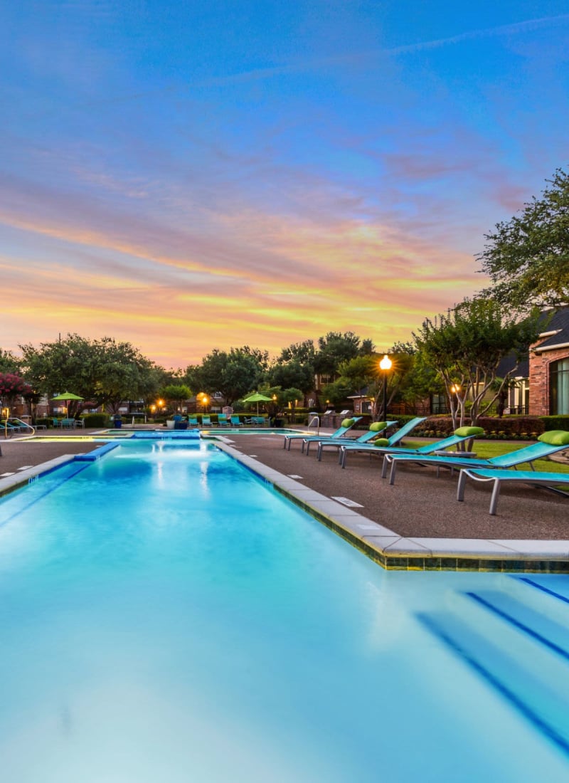 Lighted pool at sunset with sun chairs at Marquis at Stonebriar in Frisco, Texas