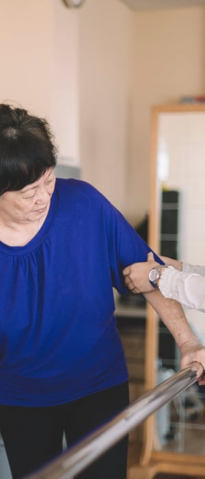 Resident in rehabilitation therapy walking with hand-rails at WISH