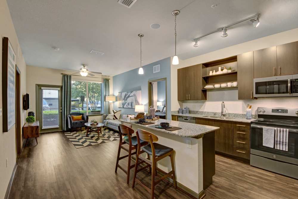 Open kitchen with stainless-steel appliances and island countertop at The Courtney at Lake Shadow in Orlando, Florida 