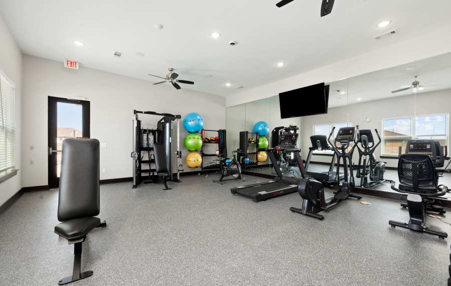 Modern fitness center with cardio machines, weights, exercise balls, and large mirrors at Preserve at Gresham Lake in Raleigh, North Carolina