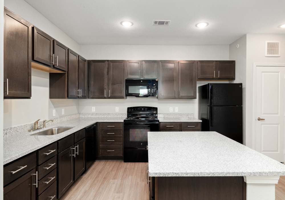 Modern kitchen with granite countertops and refrigerator at Redwood in San Marcos, Texas