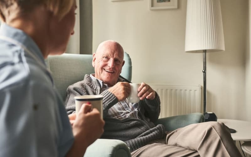 A resident having coffee with a caretaker at Grand Villa of DeLand in DeLand, Florida