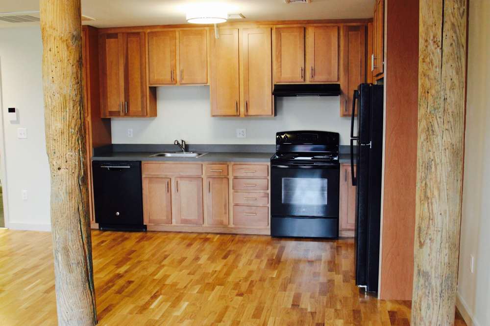 Kitchen with black appliances and hard wood flooring at Duck Mill in Lawrence, Massachusetts