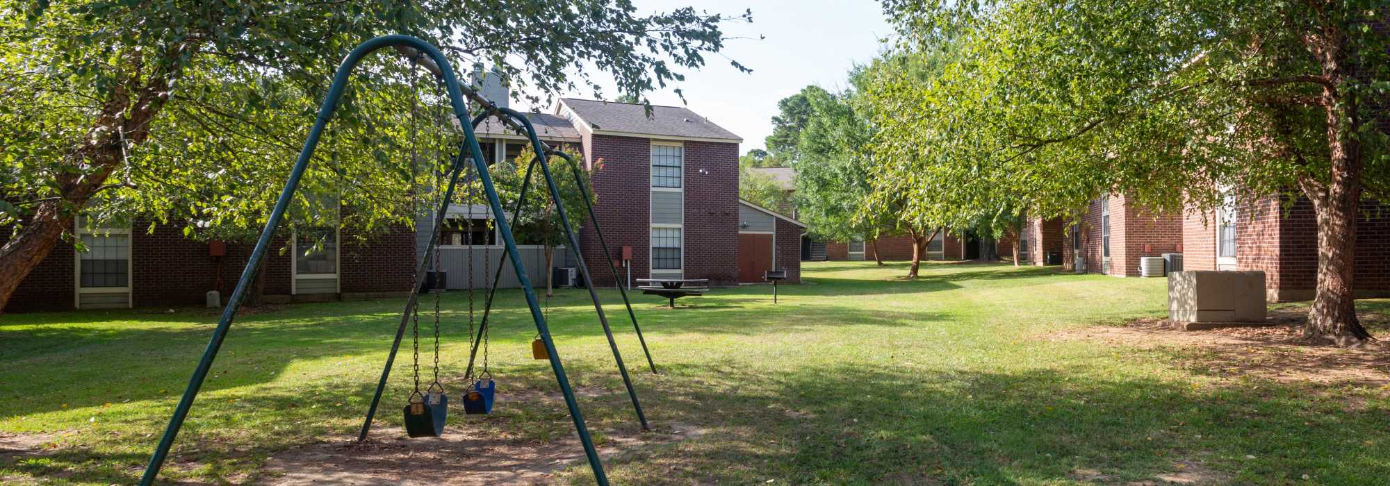 Apartment playground featuring swings and grassy area at Southwood Village in Shreveport, Louisiana