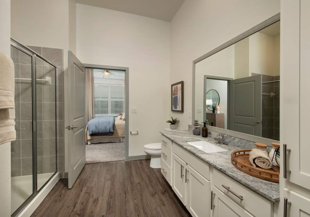 Master bathroom with sink, commode and glass shower area at Orleans at Fannin Station in Houston, Texas