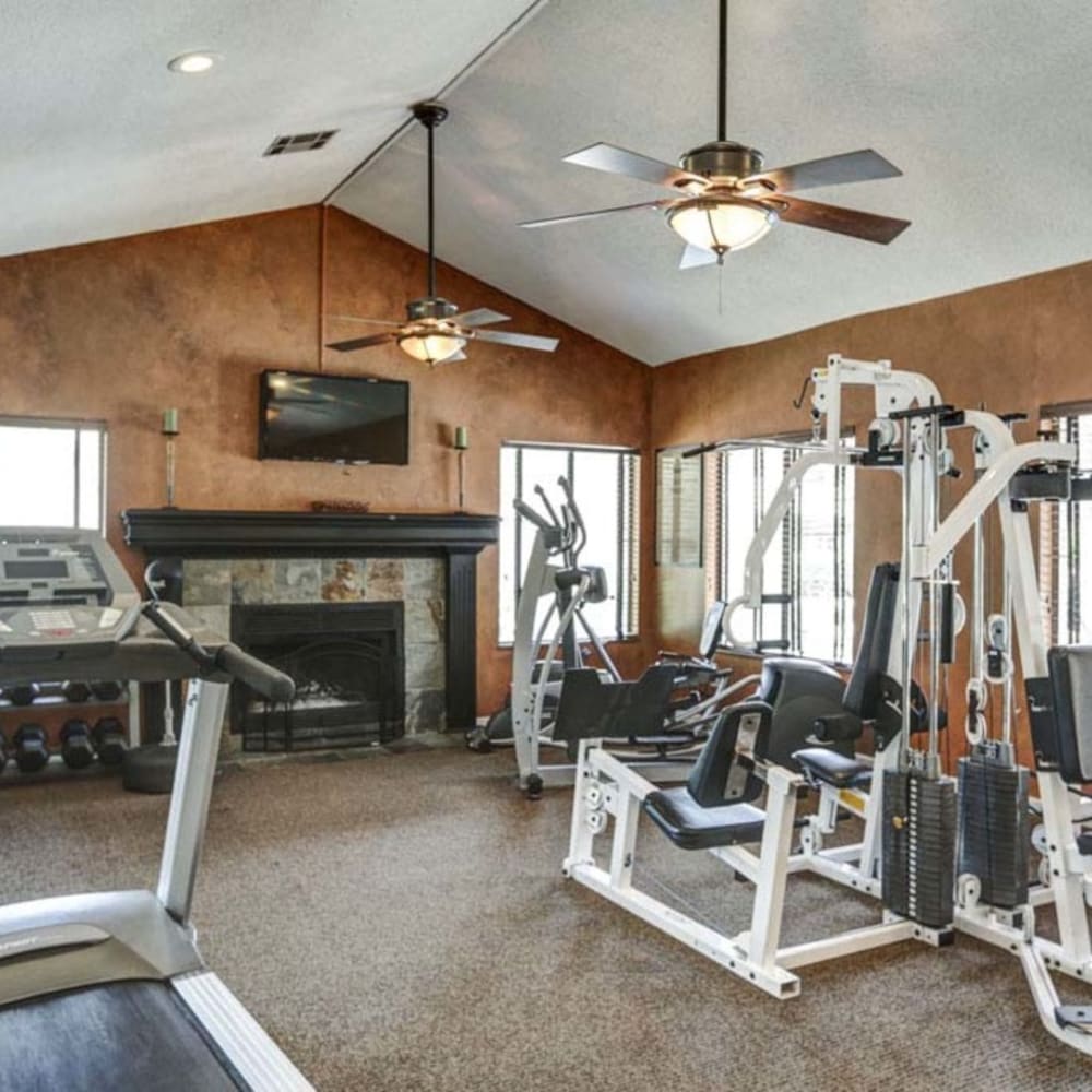 24-7 Fitness gym with exercise machines and a fireplace at Springhill Apartments in Overland Park, Kansas
