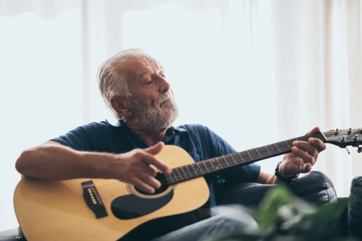 Senior man playing guitar at Oxford Vista Wichita in Wichita, Kansas