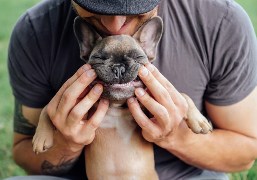 Resident holding his puppy up to smile at the camera at The Villas at Woodland Hills in Woodland Hills, California