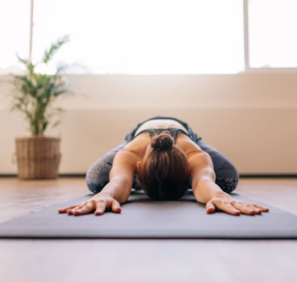 Resident stretching on a yoga mat in the onsite fitness center at Harbor Point Apartments in Mill Valley, California