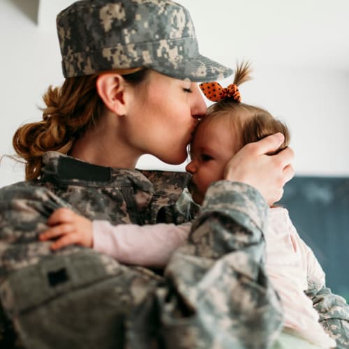 A resident in military uniform kissing her child at Adobe Flats IV in Twentynine Palms, California