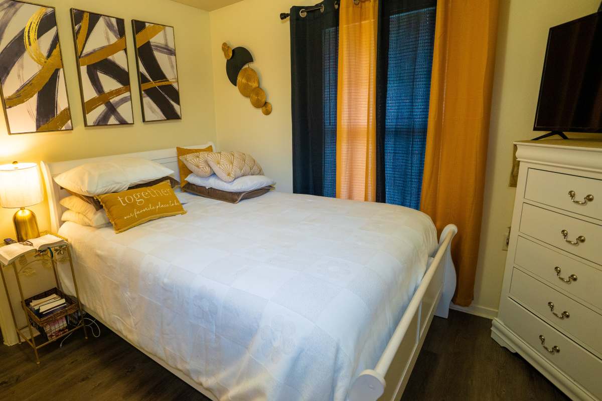 Cozy bedroom with a white bed, decorative pillows, and stylish artwork on the walls at Willowbrook I in Lafayette, Louisiana 