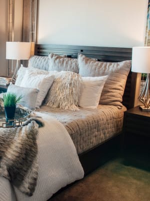 Elegant model master bedroom with hardwood style flooring at Terra at University North Park in Norman, Oklahoma