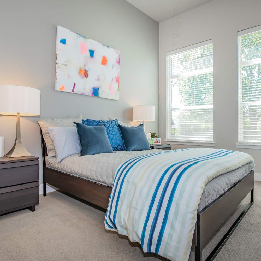 Comfortable bedroom with bed, large window and carpet flooring at Park Place Olde Town Apartments in Arvada, Colorado