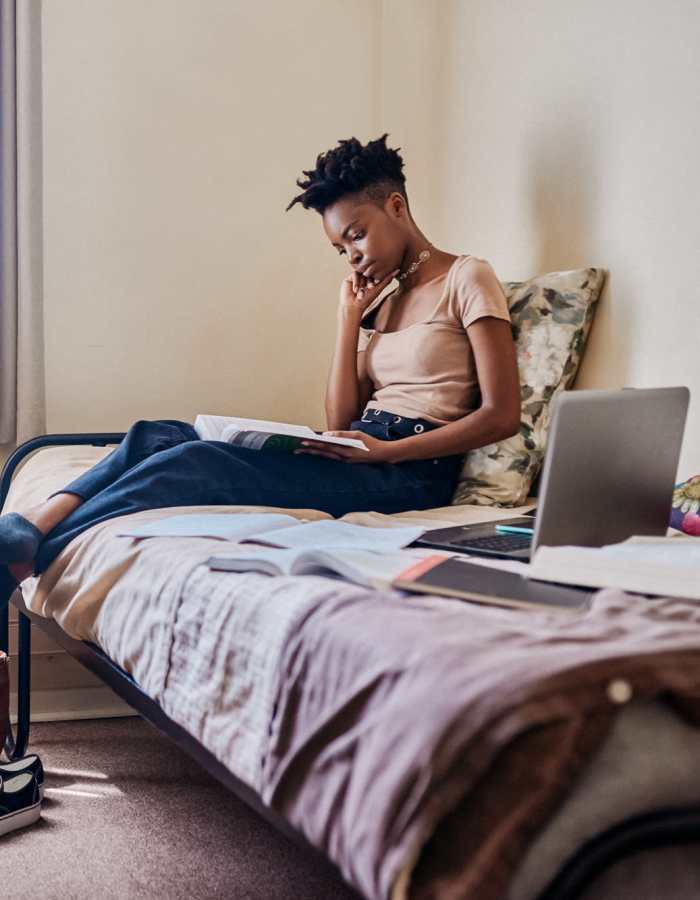 Student working on her laptop while lying on her bed at Mazza Grandmarc in College Park, Maryland