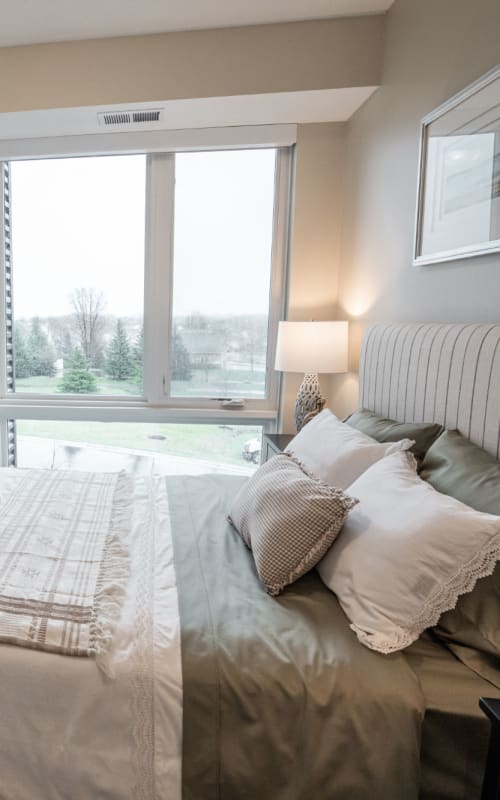 Resident apartment bedroom with large window with a scenic view at The Pillars of Lakeville in Lakeville, Minnesota