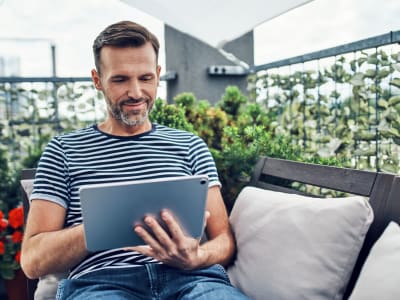 Man reads an online book on his private balcony at Lakeshore Apartments in Concord, California