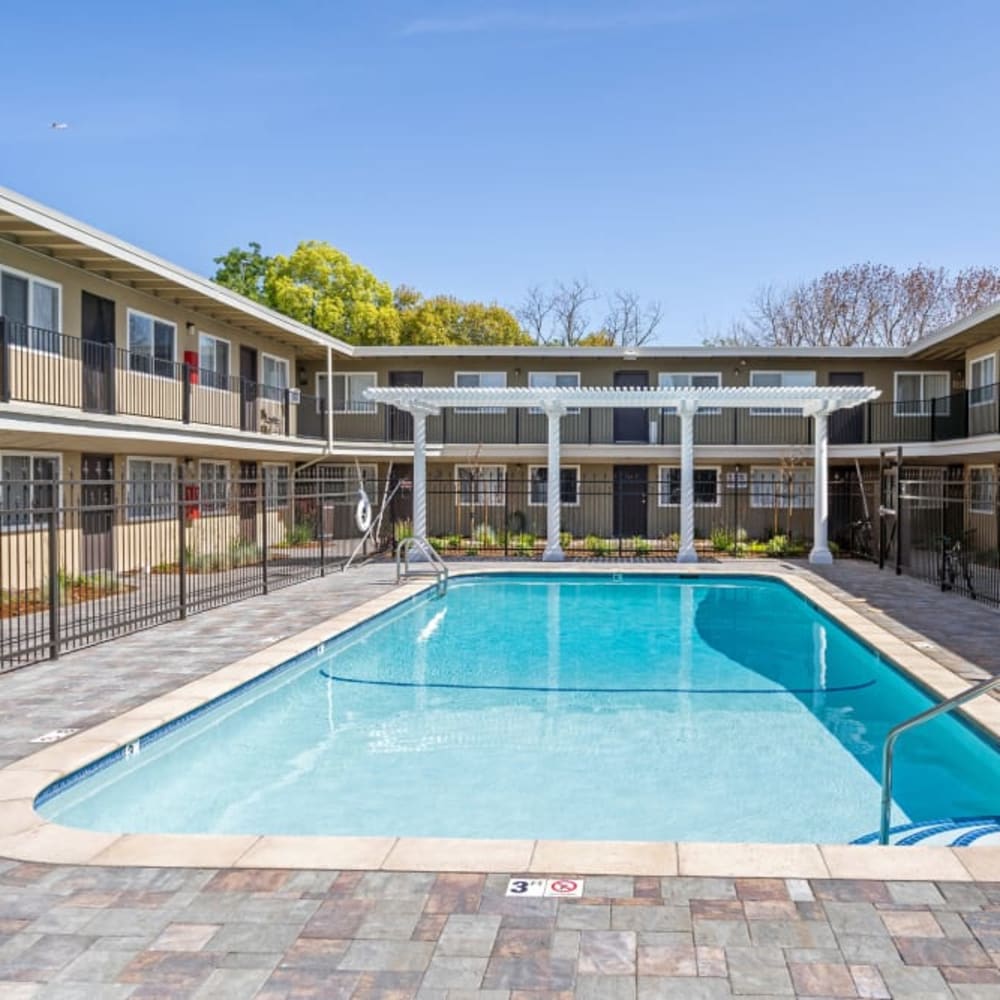 Swimming pool and pergola with lounge chairs at Royal Gardens Apartments in Livermore, California