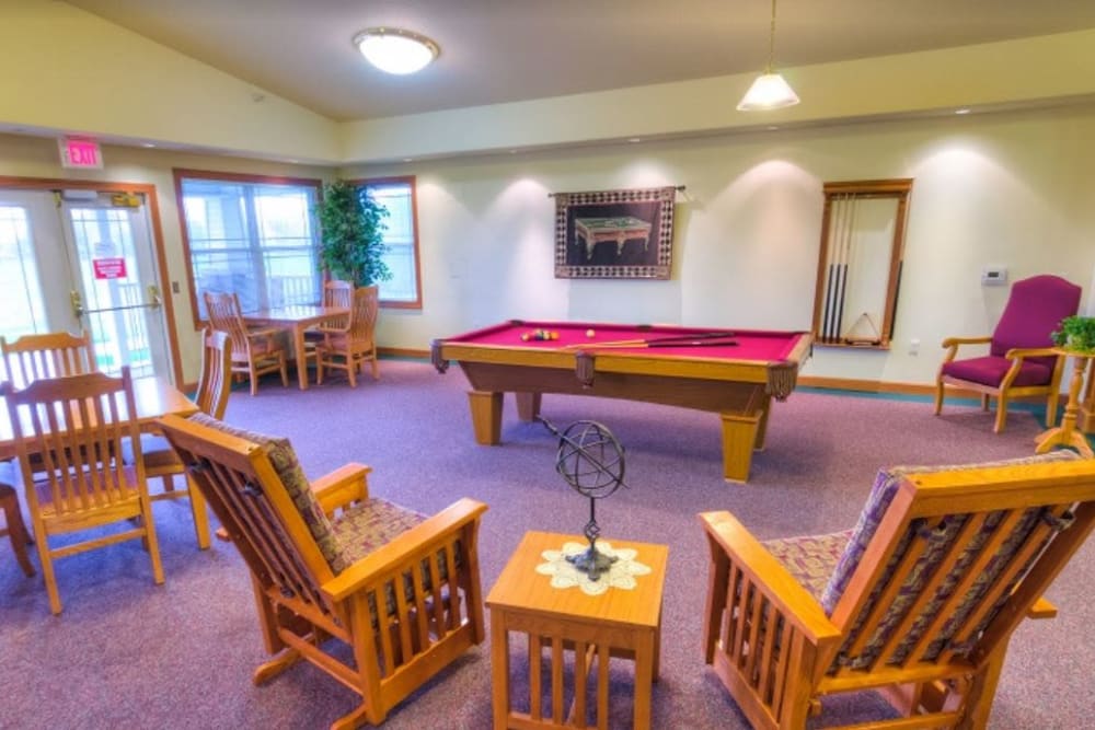 Multi purpose activity room with a pool table and plenty of seating at Addington Place of Ottumwa in Ottumwa, Iowa