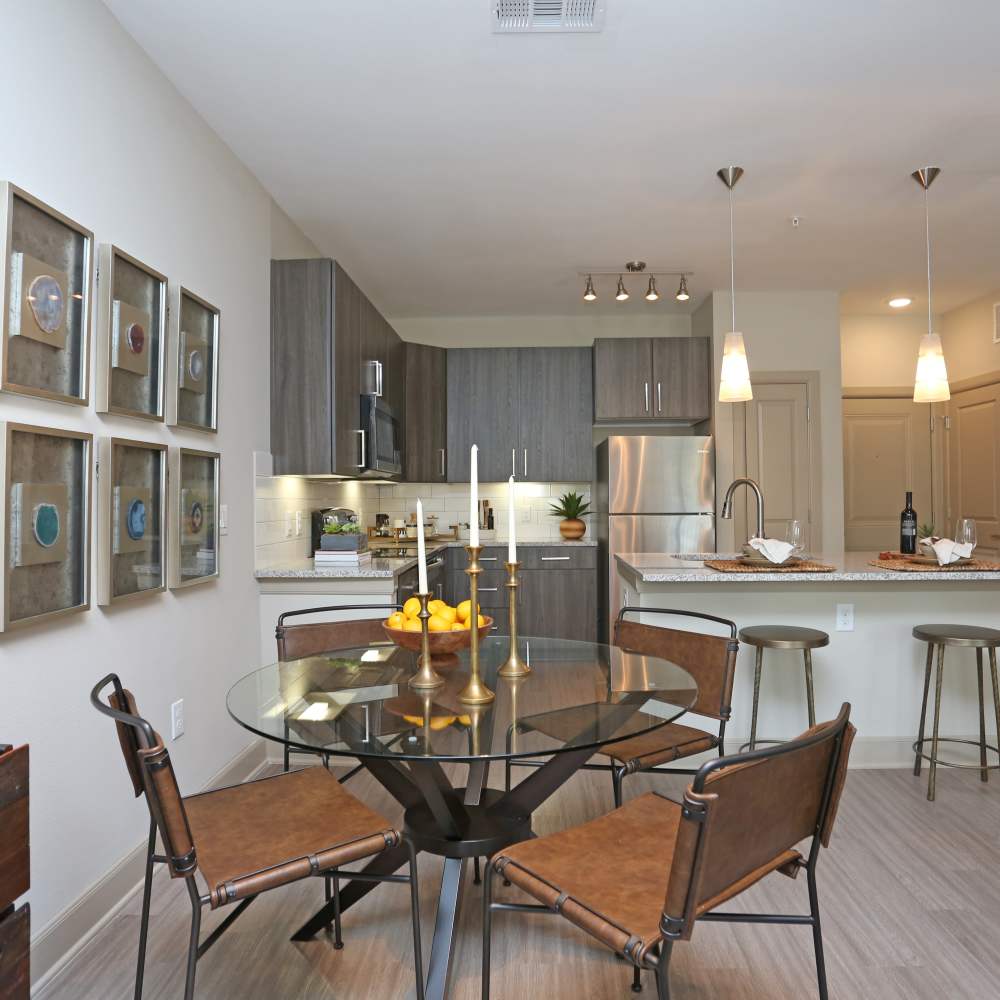 Dining area adjacent to kitchen with round glass dining table and chairs at NOVU New Forest in Houston, Texas