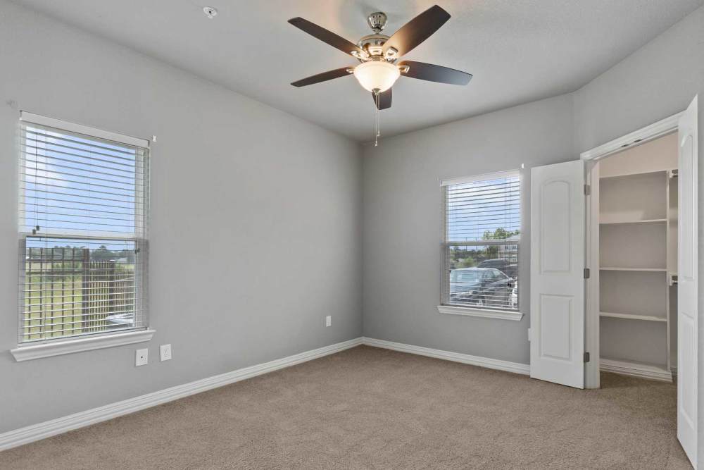 Carpet floored bedroom with ceiling fan and walk-in closets at Pine Creek in Paris, Texas