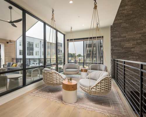 Lounge area with swing chairs and large windows with view of the outside community at Clovis Point in Longmont, Colorado