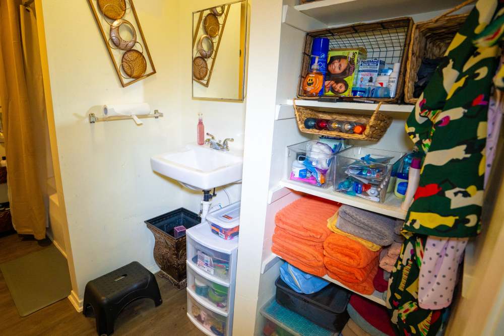 Bright bathroom with a sink, storage shelves, and colorful towels neatly organized at Willowbrook I in Lafayette, Louisiana