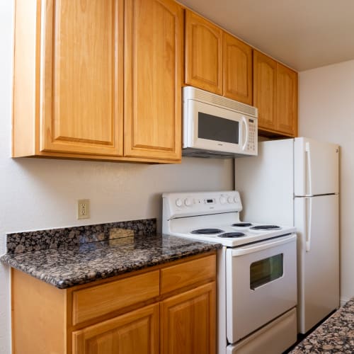 Kitchen with white appliances and built-in microwave at Peppertree Apartments in San Jose, California