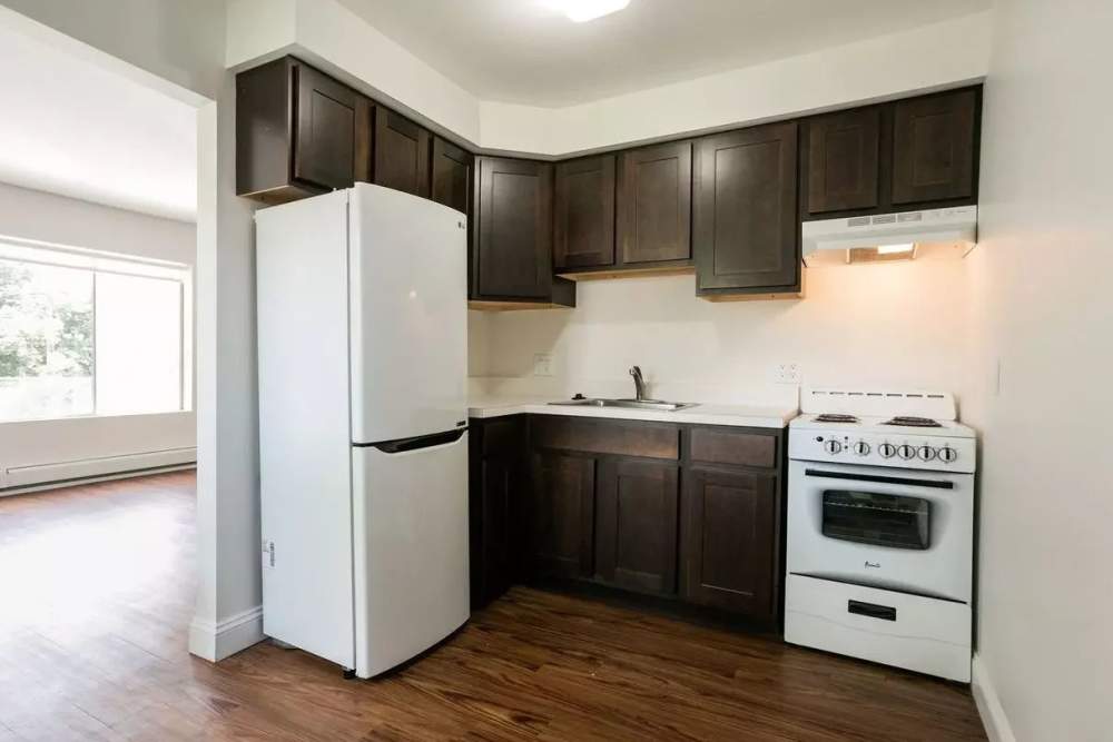 Apartment kitchen with white appliance and dark cabinetry at Detroit Living in Detroit,Michigan