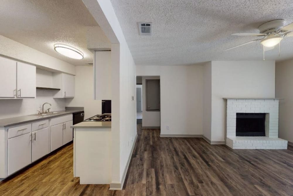 Apartment living room and kitchen with wood style flooring at The Haylie in Garland, Texas