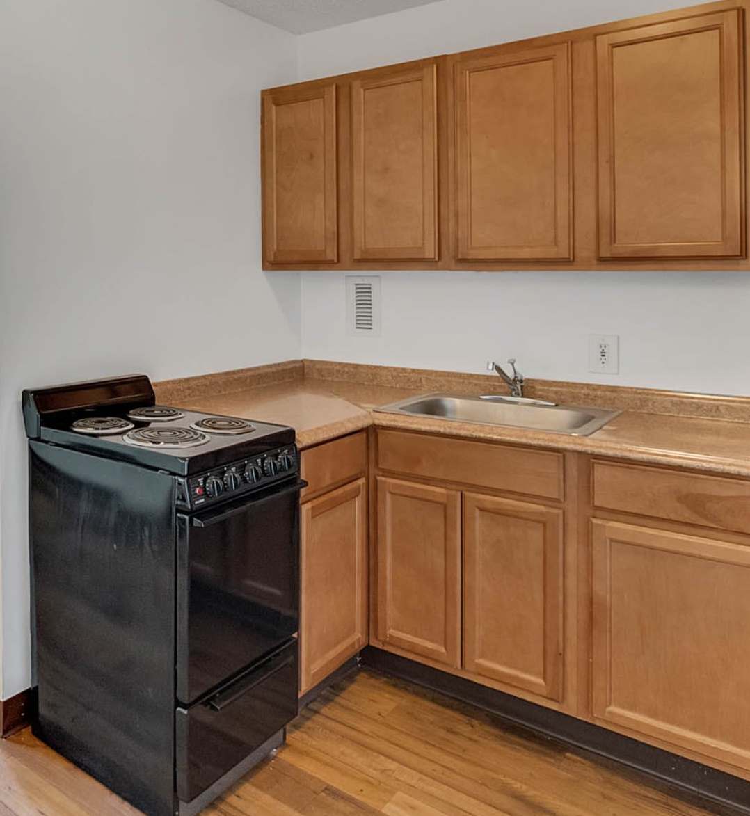 Apartment kitchen with black stove and wooden cabinets at Bay Pointe Tower in South Pasadena, Florida