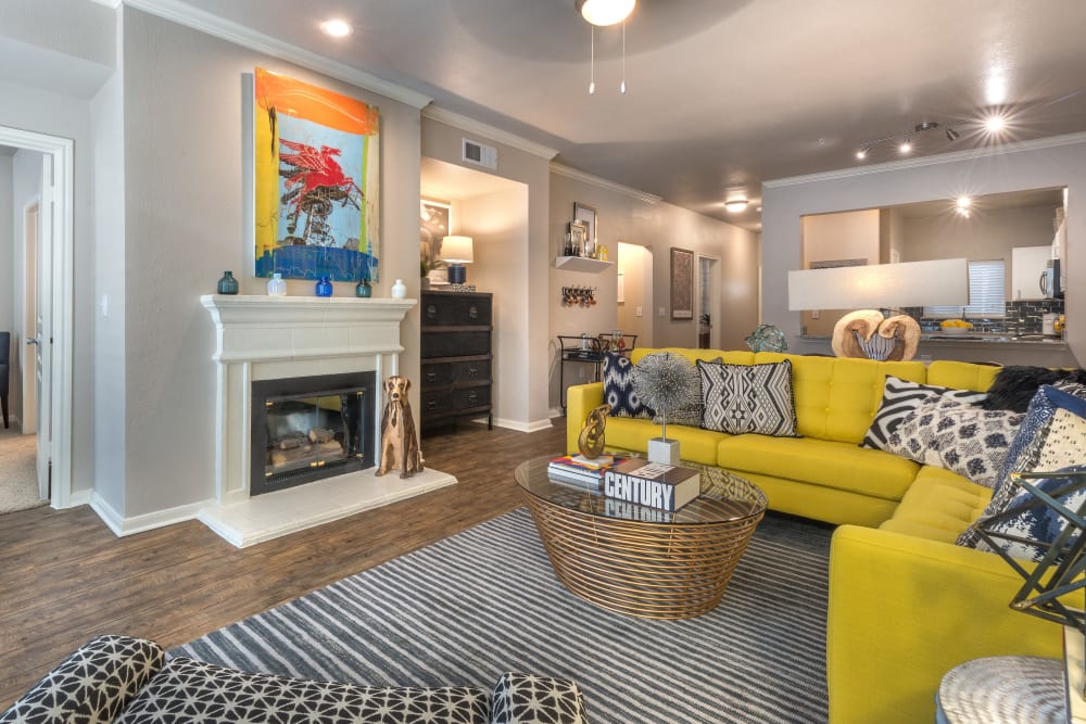 Model living room with a ceiling fan and a fireplace at 75 West in Dallas, Texas