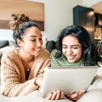 Two women laying on a couch in their apartment at The Lively Indigo Run in Ladson, South Carolina