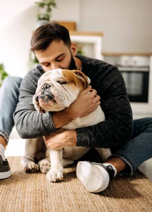 Man sitting on floor hugging a dog at Keystone at Horse Pen Creek in Greensboro, North Carolina